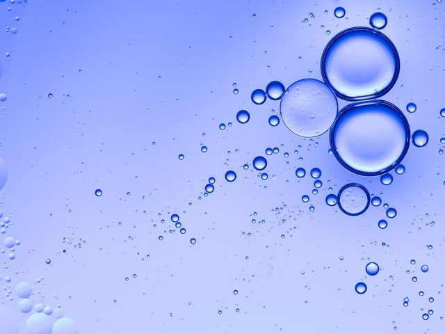Oil drops and bubbles floating over water with a blue background