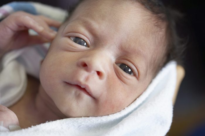 Close up of newborn African baby in blanket