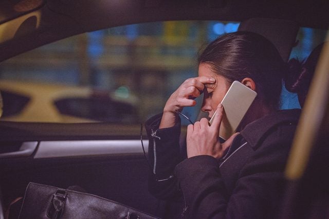Young woman using smart phone on the front seat of the car at night