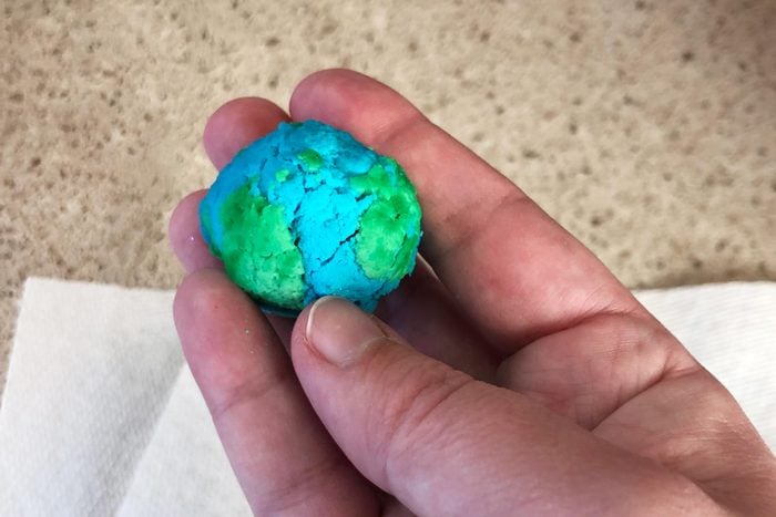 hand holding a model of the earth made from milk plastic