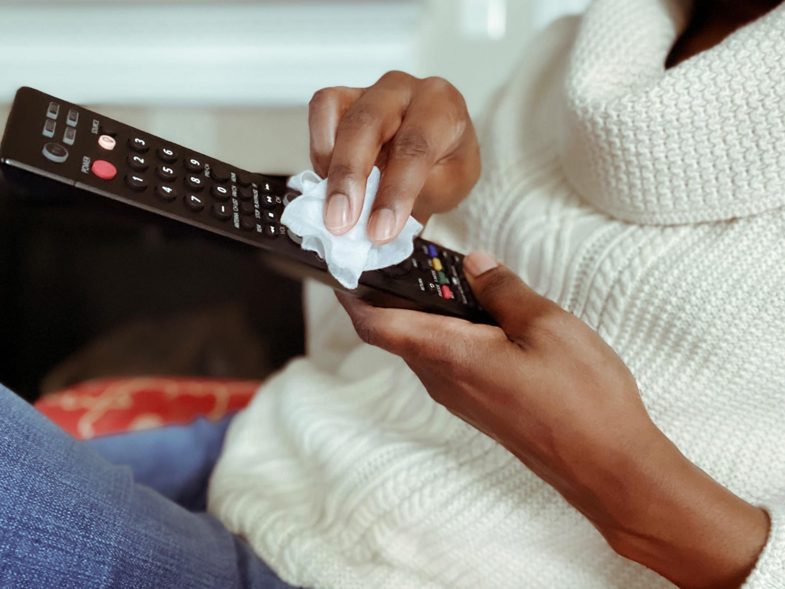 Woman disinfecting the TV remote during spring cleaning