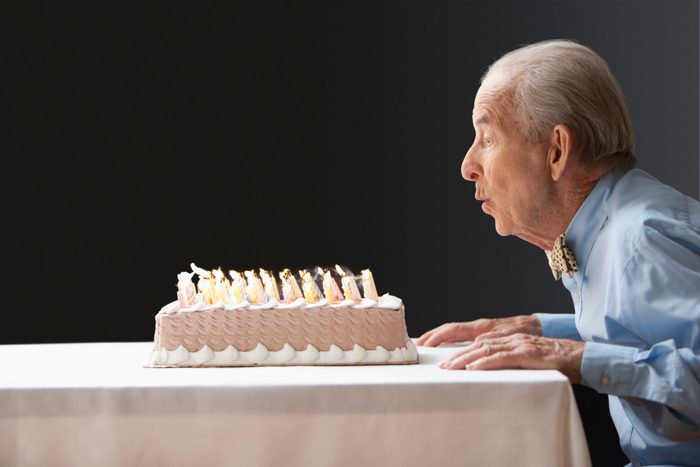 Senior Hispanic man blowing out birthday candles