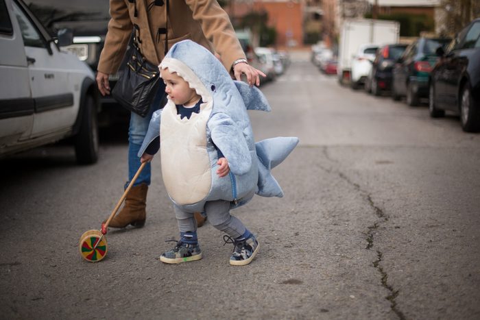 Toddler dressed as a shark crossing the road with grandma