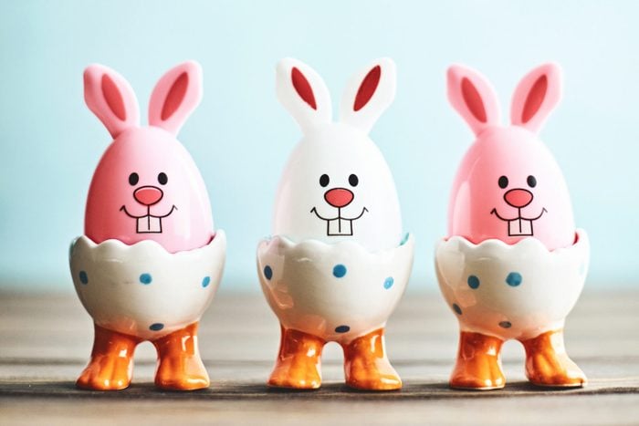 Cute Easter bunny trio in eggcups with blue background
