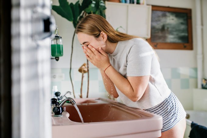 Woman in bathroom washing face