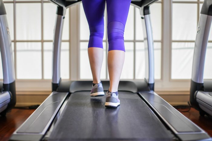Low Section Of Woman Running On Treadmill At Gym