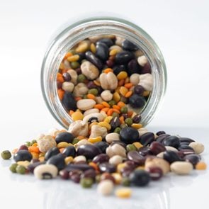 Close-Up Of Lentils and Beans Spilling From a glass Jar On White Background