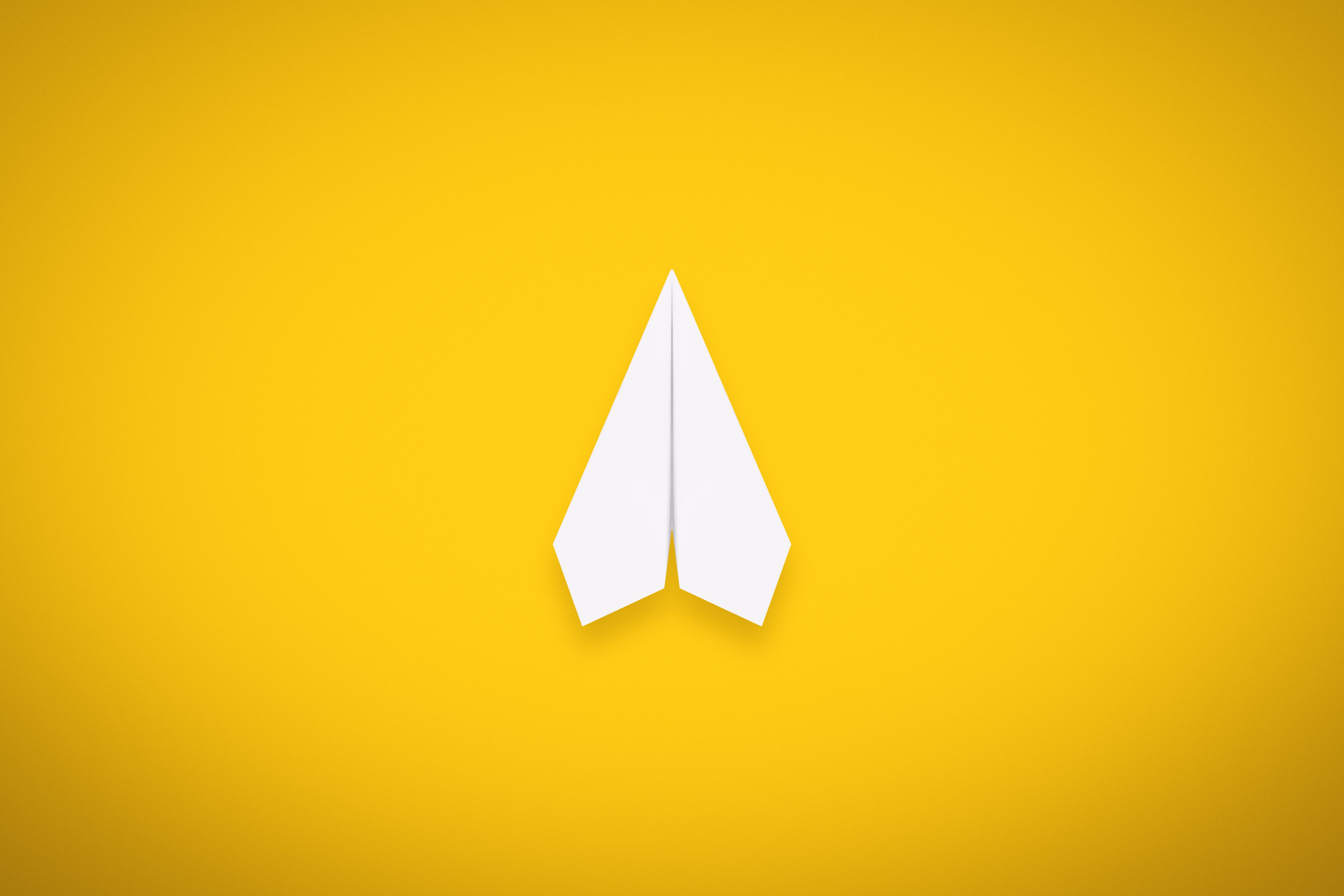 A Single Paper Airplane on Yellow Background