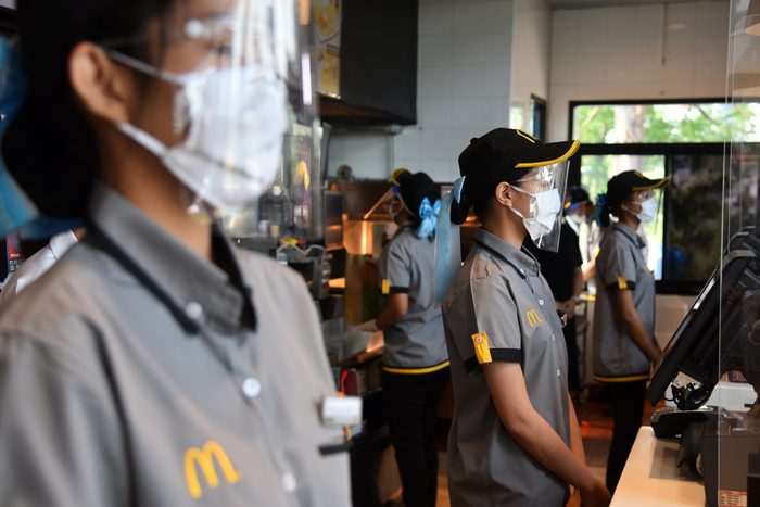 An employee of McDonald's wearing a protective mask and a...