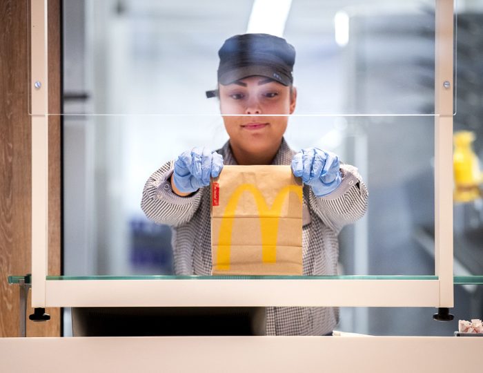 A McDonalds' employee holds up a food package at a test location in a restaurant at The GelreDome Arnhem, The Netherlands on May 1, 2020, as part of measures to attempt to stop the spread of COVID-19 (novel coronavirus). - In this restaurant prototype, the fast food chain shows what seated catering in the 1.5 meter economy could look like. There are two variants: Take Out Plus and Dine In. (Photo by Remko DE WAAL / ANP / AFP) / Netherlands OUT (Photo by REMKO DE WAAL/ANP/AFP via Getty Images)