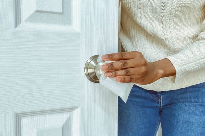 Woman Cleans Interior Doorknob Using Disinfectant Wipe