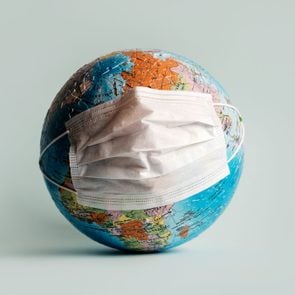 Globe made of jigsaw puzzles with a protective medical mask