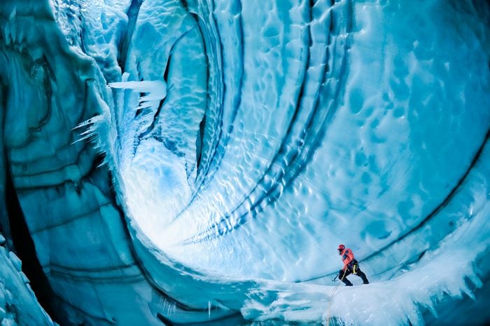 Male ice climber exploring ice cave, low angle view