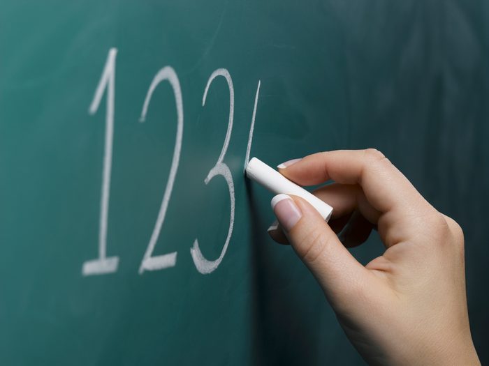 Woman writing numbers on chalkboard, close-up