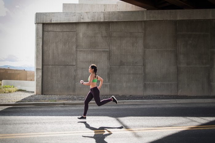 Young woman running under freeway overpass