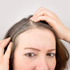 woman examining her grey hair roots