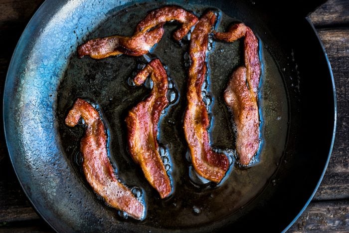 High Angle View Of Bacon In Frying Pan On Wooden Table