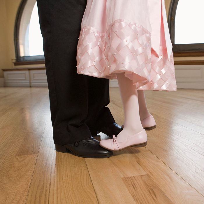 Daughter standing on feet of father dancing