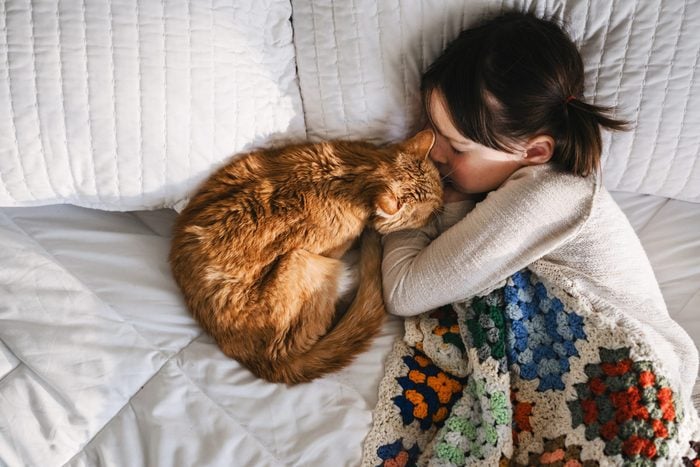 Girl having a nap on a bed with her cat