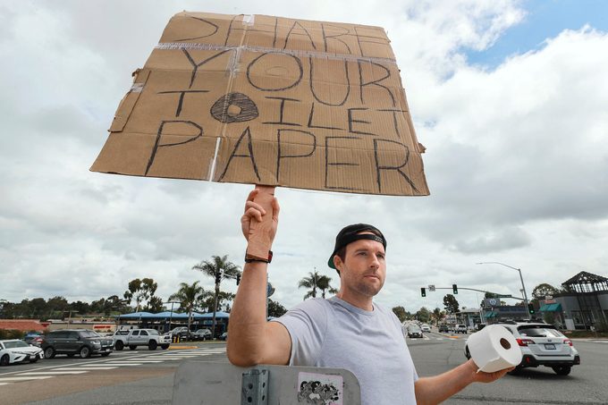 Jonny Blue holding his sign that reads, "share your toilet paper"