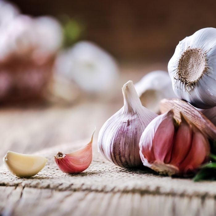 Garlic cloves on rustic table. Garlic in wooden bowl. Fresh peeled garlic and bulbs.