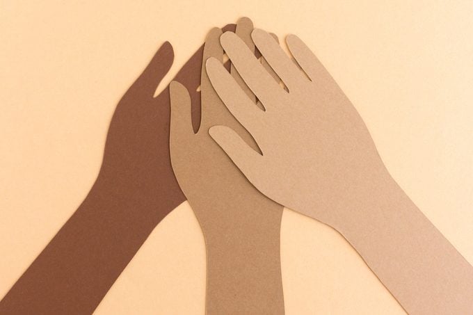 paper cutouts of diverse hands coming together. bipoc.