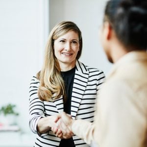 Smiling businesswoman shaking hands with client before meeting