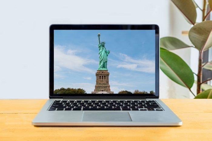 laptop screen on a simple desk showing the statue of liberty