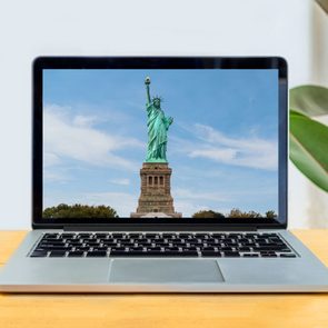 laptop screen on a simple desk showing the statue of liberty