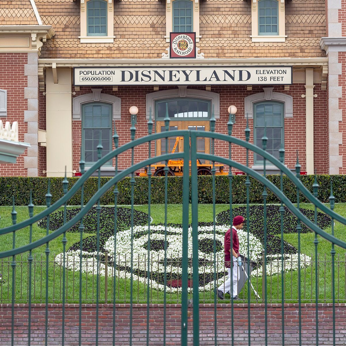 An employee cleans the grounds behind the closed gates of Disneyland Park on the first day of the closure of Disneyland and Disney California Adventure theme parks as fear of the spread of coronavirus continue, in Anaheim, California, on March 14, 2020. - The World Health Organization said March 13, 2020 it was not yet possible to say when the COVID-19 pandemic, which has killed more than 5,000 people worldwide, will peak. "It's impossible for us to say when this will peak globally," Maria Van Kerkhove, who heads the WHO's emerging diseases unit, told a virtual press conference, adding that "we hope that it is sooner rather than later". (Photo by DAVID MCNEW / AFP) (Photo by DAVID MCNEW/AFP via Getty Images)