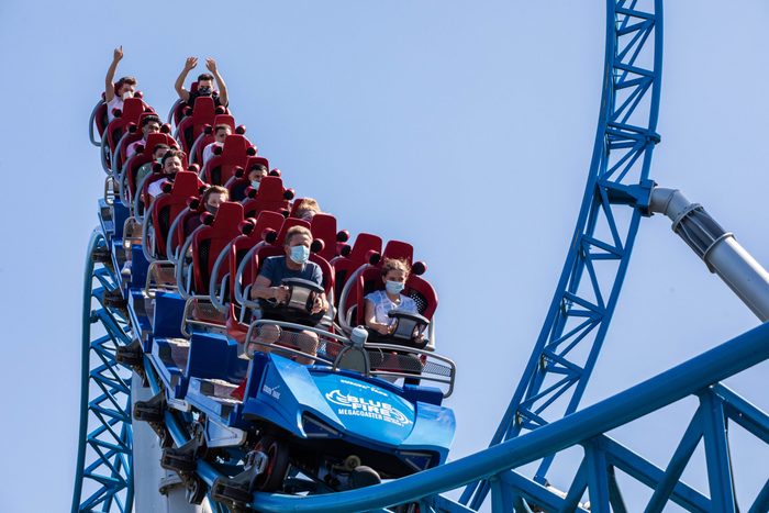 Masked people separated on a running roller coaster