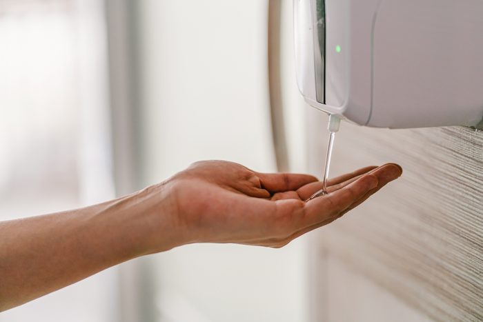 Closeup Asian woman hand using wash hand sanitizer gel dispenser automatic machine