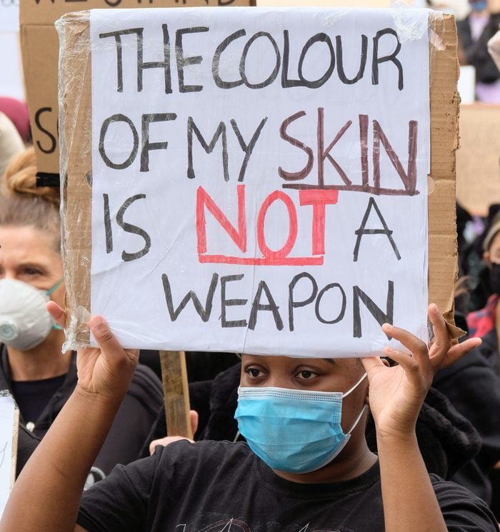 A protester wearing a face mask holds a placard saying the...