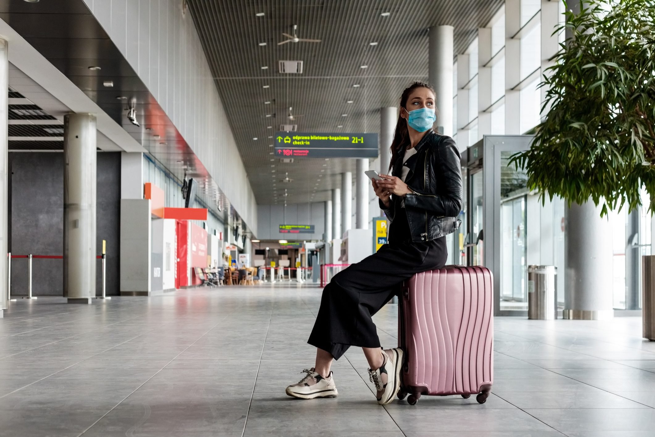 Young woman at the airport with luggage, wearing N95 face masks