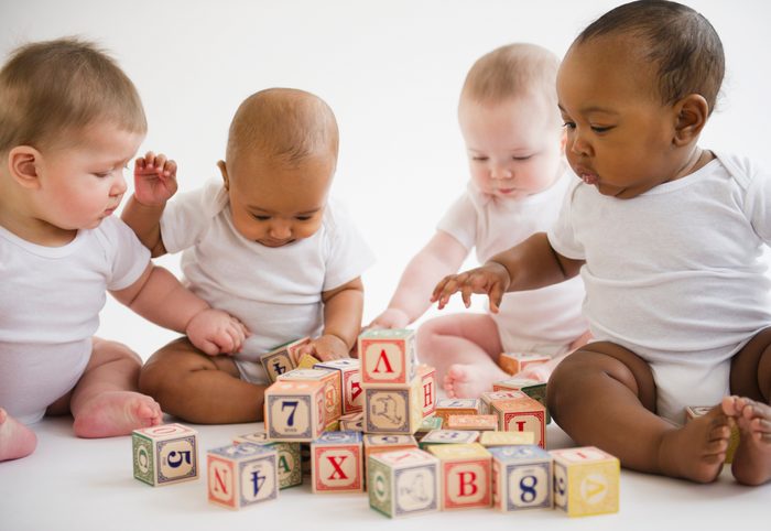 Babies sitting on floor playing with blocks