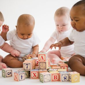 Babies sitting on floor playing with blocks