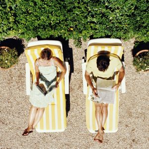Couple lying on sunbeds reading, overhead view