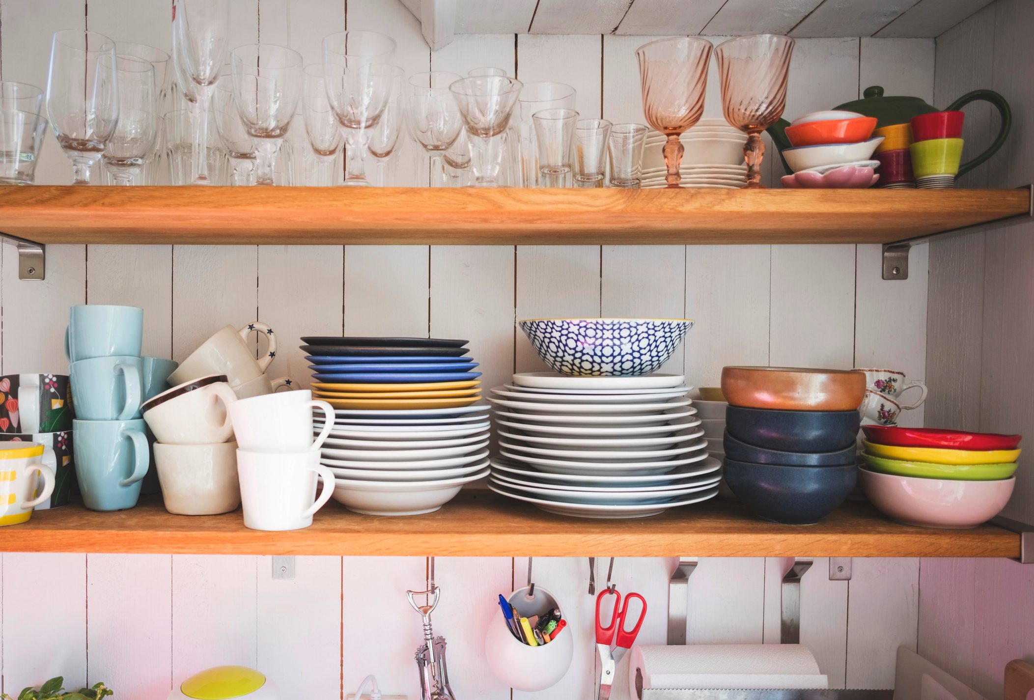 Crockery and drinking glasses on shelves in kitchen at home