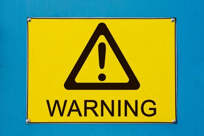 Warning sign on yellow metallic board