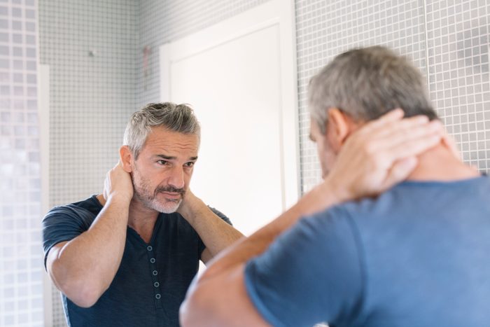 Mature man looking in bathroom mirror