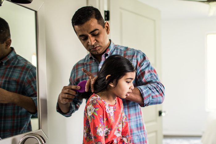 Father brushing daughters hair in bathroom