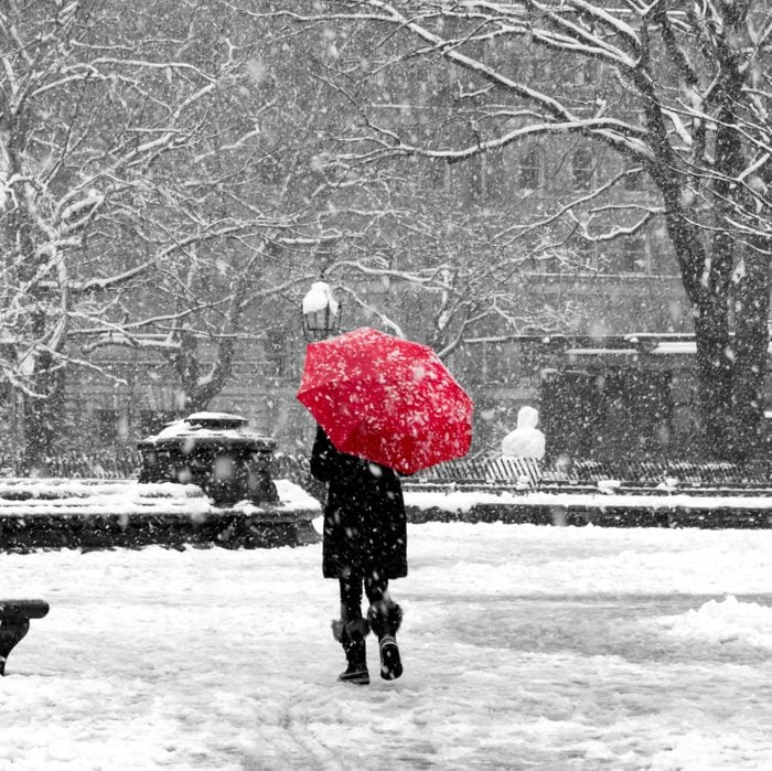 Woman with red umbrella in black and white snowstorm, New York City