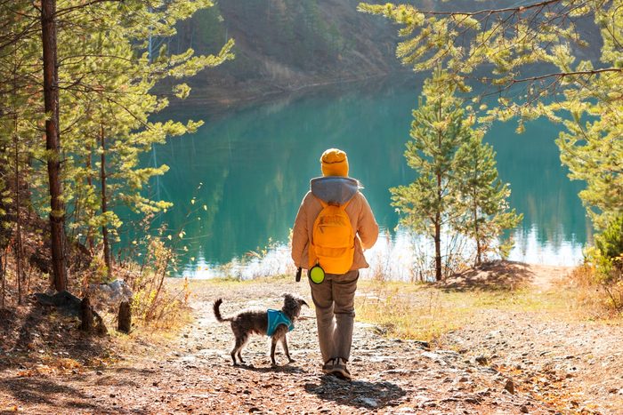 woman and her dog hiking to a beautiful alpine lake in the mountains