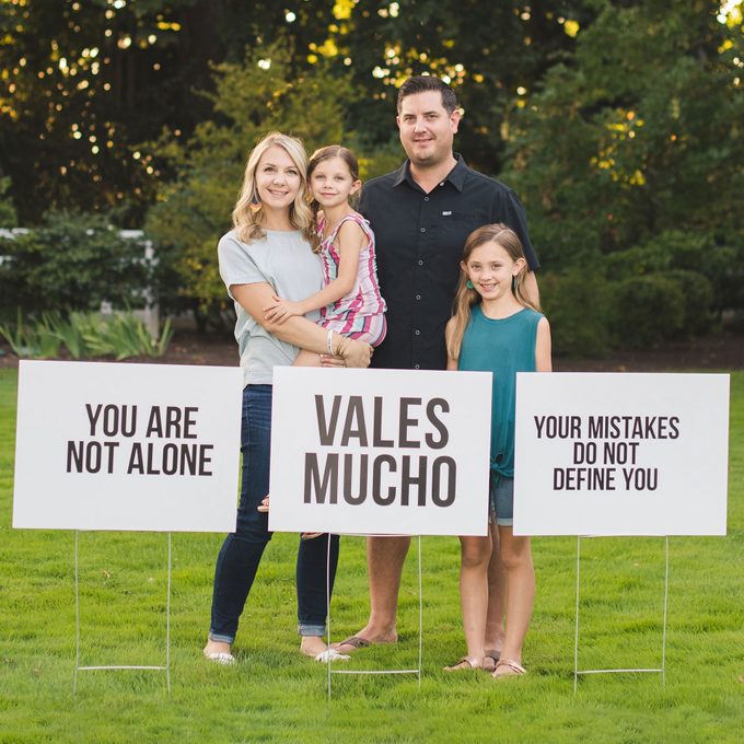 the Wolff family posing with signs they planted around newberg, oregon