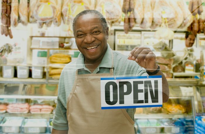 African butcher holding ""Open"" sign