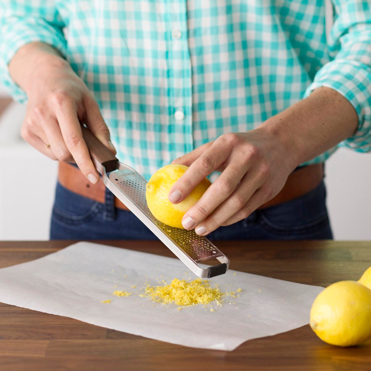 Person using a microplane to zest a lemon