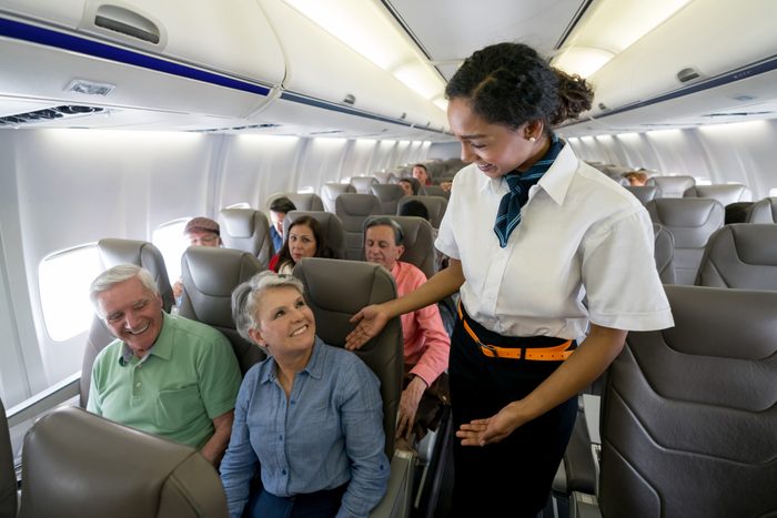Flight attendant checking on a senior couple in an airplane