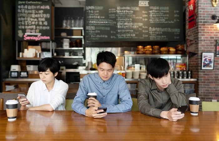 three asian people looking mobile phone