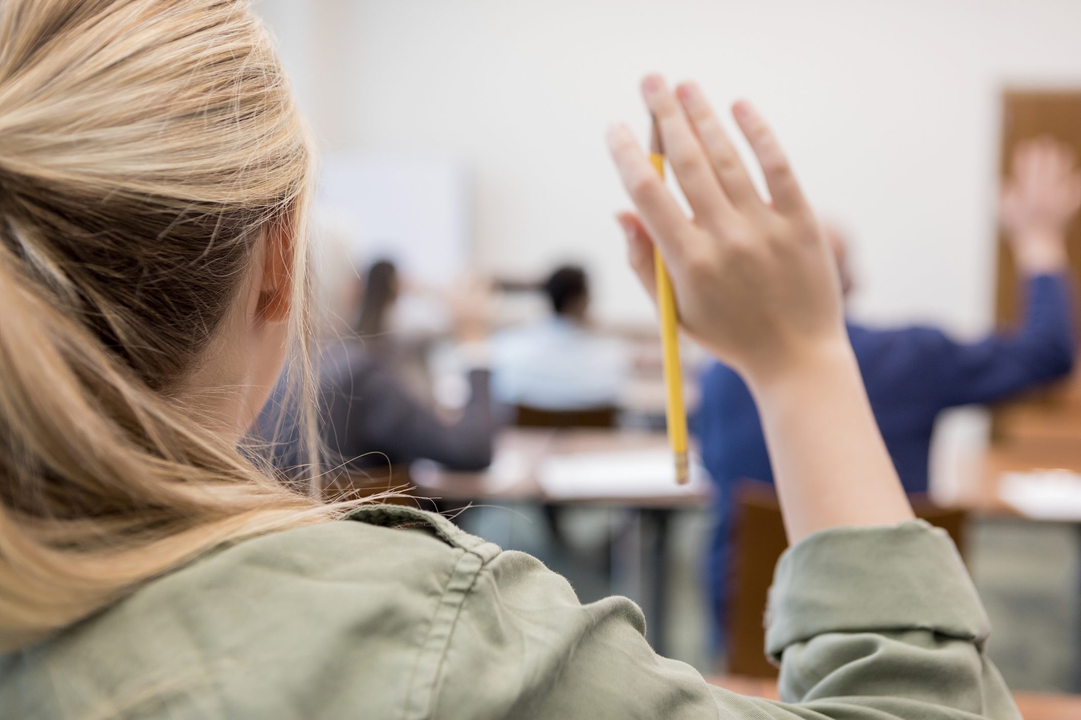 Unrecognizable Caucasian teen raises hand in class
