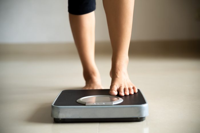 Low Section Of Woman Standing On Weight Scale At Home